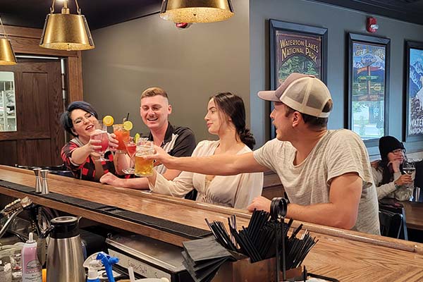 Four friends enjoying drinks at the bar, sharing a cheers.